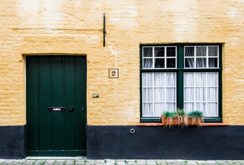 The side of a building with a large wooden door and double window.